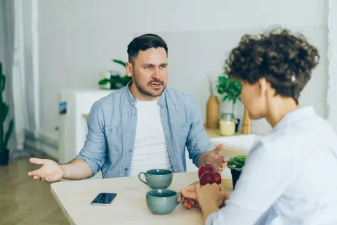 Un père discute, attablé, avec une intervenante qui l’écoute.